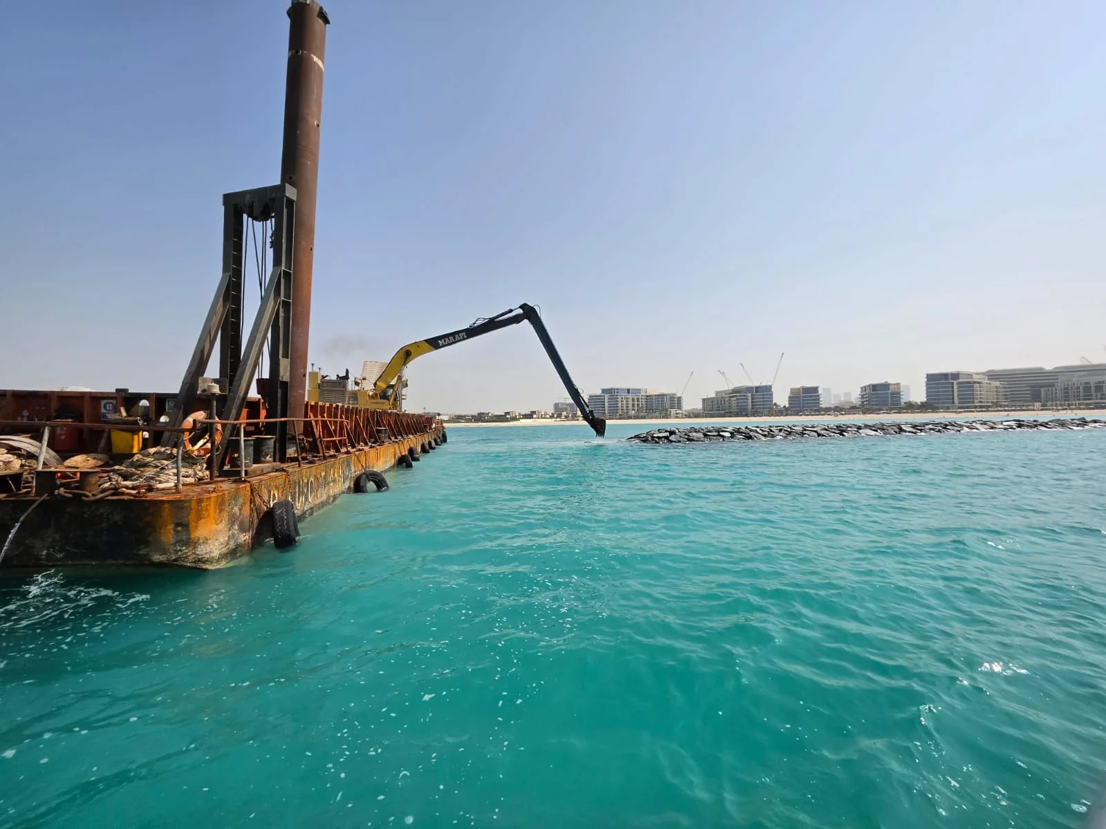 Barge and excavator operating offshore at the Mamsha and Nobu project.